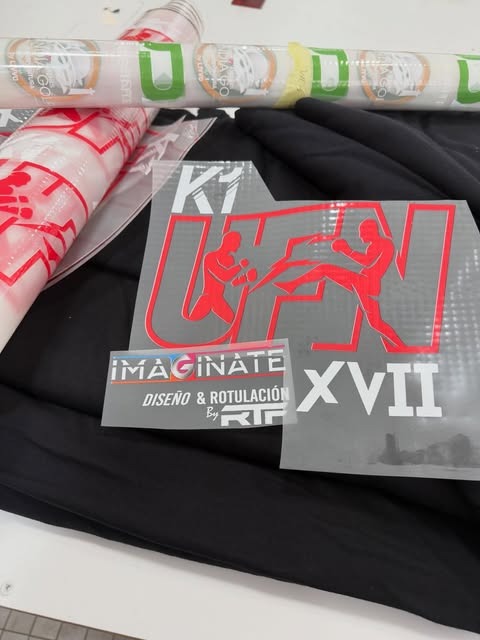 Prendas negras y diseños de impresión textil en rojo y blanco preparados en el taller
